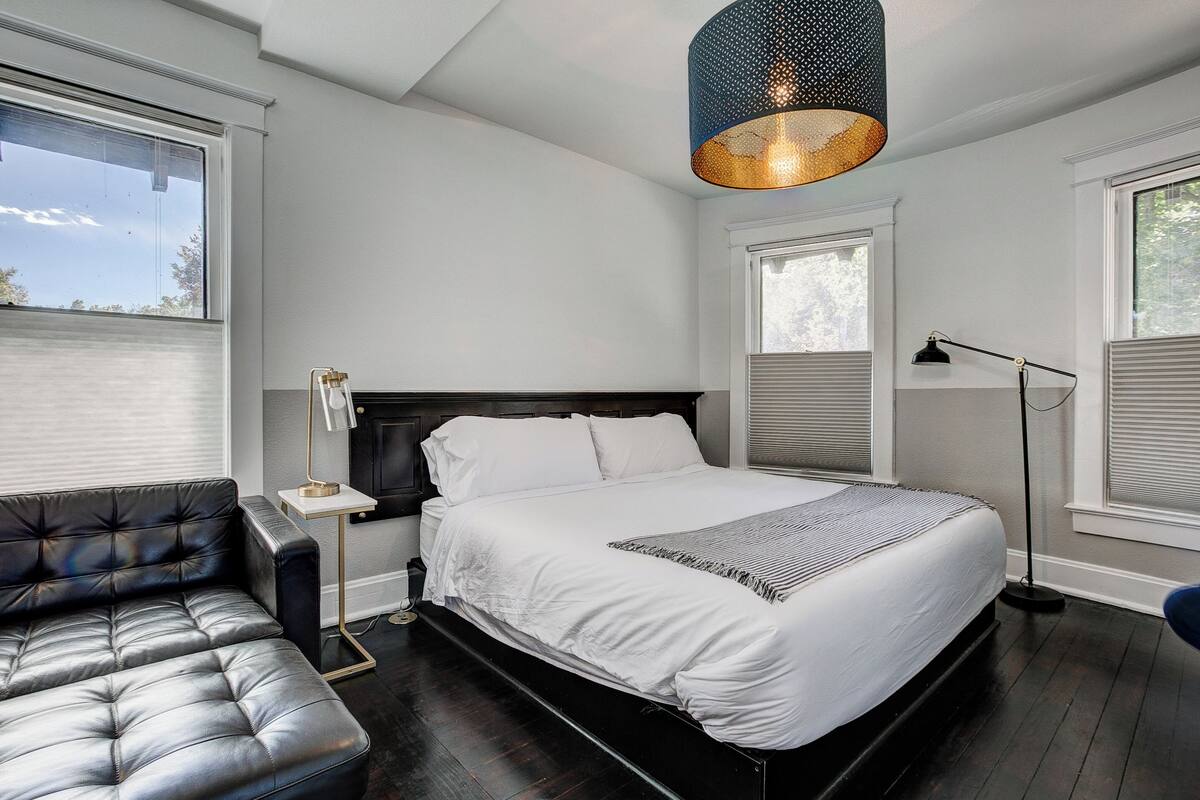 Ein Schlafzimmer mit einem großen Bett, einem Ledersofa, einem Nachttisch und einer Stehlampe.