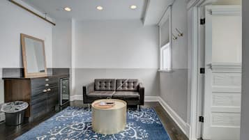 A modern living room with a dark brown leather sofa, a round coffee table, and a patterned rug.