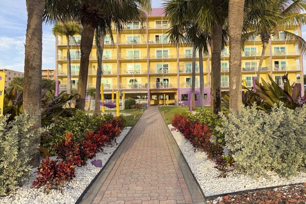 A multi-story hotel with a central courtyard, surrounded by palm trees and a variety of plants. - Fantastic Beachfront Views at Premier Beach Resort w/ Heated Pool, Top Attraction Tickets Included. (Treasure Island)