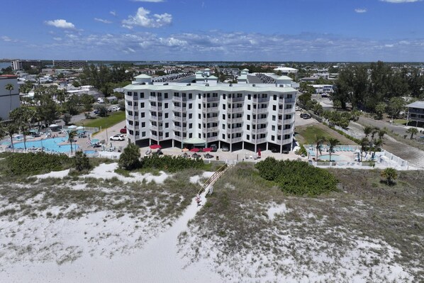 A multi-story hotel with a pool area, surrounded by greenery and a beach. - Beachfront Resort.  Balcony with Partial Beach View.  Pools, Cafe, Bar, Fitness Center & Parking (Treasure Island)