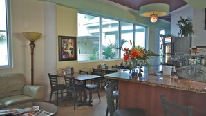 Un vaste espace dédié à la salle à manger, avec de nombreuses tables et chaises, un comptoir de bar et de grandes fenêtres offrant une vue sur l’extérieur.