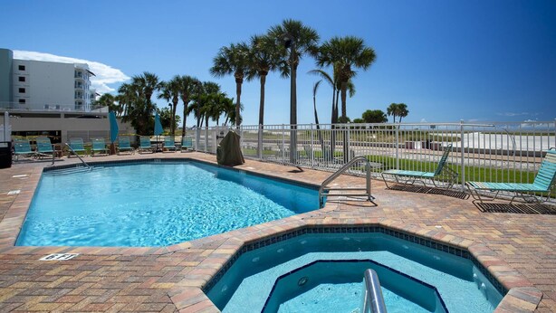A swimming pool with a hot tub, surrounded by palm trees and a view of the ocean. - Beachfront Overlooking the Pool and Beach - Heated Pool, Great Location (Treasure Island)