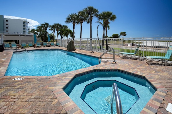 A swimming pool with a hot tub, surrounded by palm trees and a view of the ocean. - Beachfront Overlooking the Pool and Beach - Heated Pool, Great Location (Treasure Island)