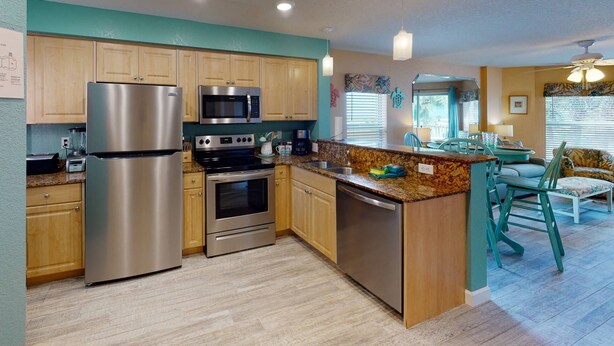 A modern kitchen with stainless steel appliances, wooden cabinets, and a granite countertop.