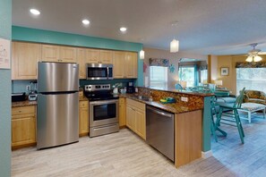 Una cocina moderna con electrodomésticos de acero inoxidable, armarios de madera y encimera de granito.