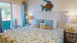 A bedroom with a bed, a nightstand, a chair, a window, and a wall decoration.