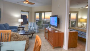 A spacious living area with a television, seating, and a view of the sunset. - Gulf Views from Balcony. Heated Pool. Beautiful Property Directly Across from the Beach! (Treasure Island)