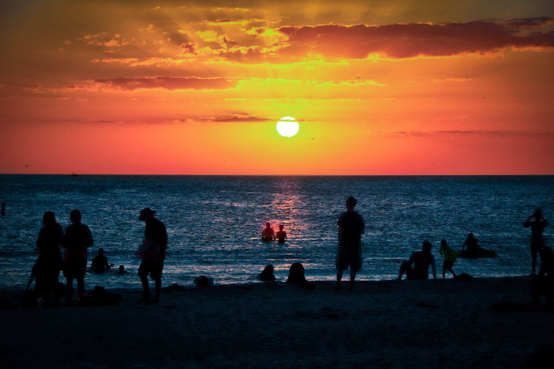 A beach scene with people at sunset.