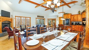 Amplia sala de estar con chimenea, comedor para seis personas y cocina con armarios de madera.