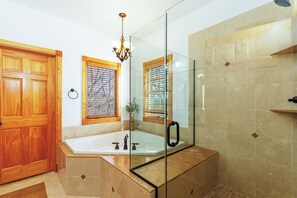 Een bad/douchecombinatie, een bubbelbad, een haardroger, handdoeken