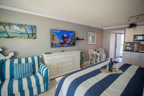 Una habitación con cama, sofá, televisión, zona de comedor y cocina.