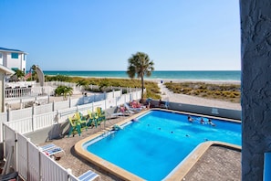 Une piscine avec des chaises longues et vue sur la plage.