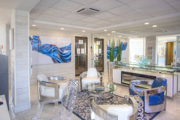 A modern lobby with a glass reception desk, white leather chairs, and abstract art on the walls.
