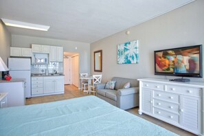 A compact living space with a kitchenette, a sofa, a TV, and a dining area. - Relaxed Beachfront Escape Together: Beach, Pool, Private Balcony, Tiki Bar, and Grill, Fishing Dock (Treasure Island)