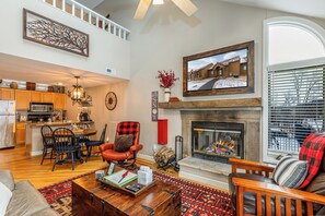 A spacious living room with a fireplace, a dining area, and a kitchen.