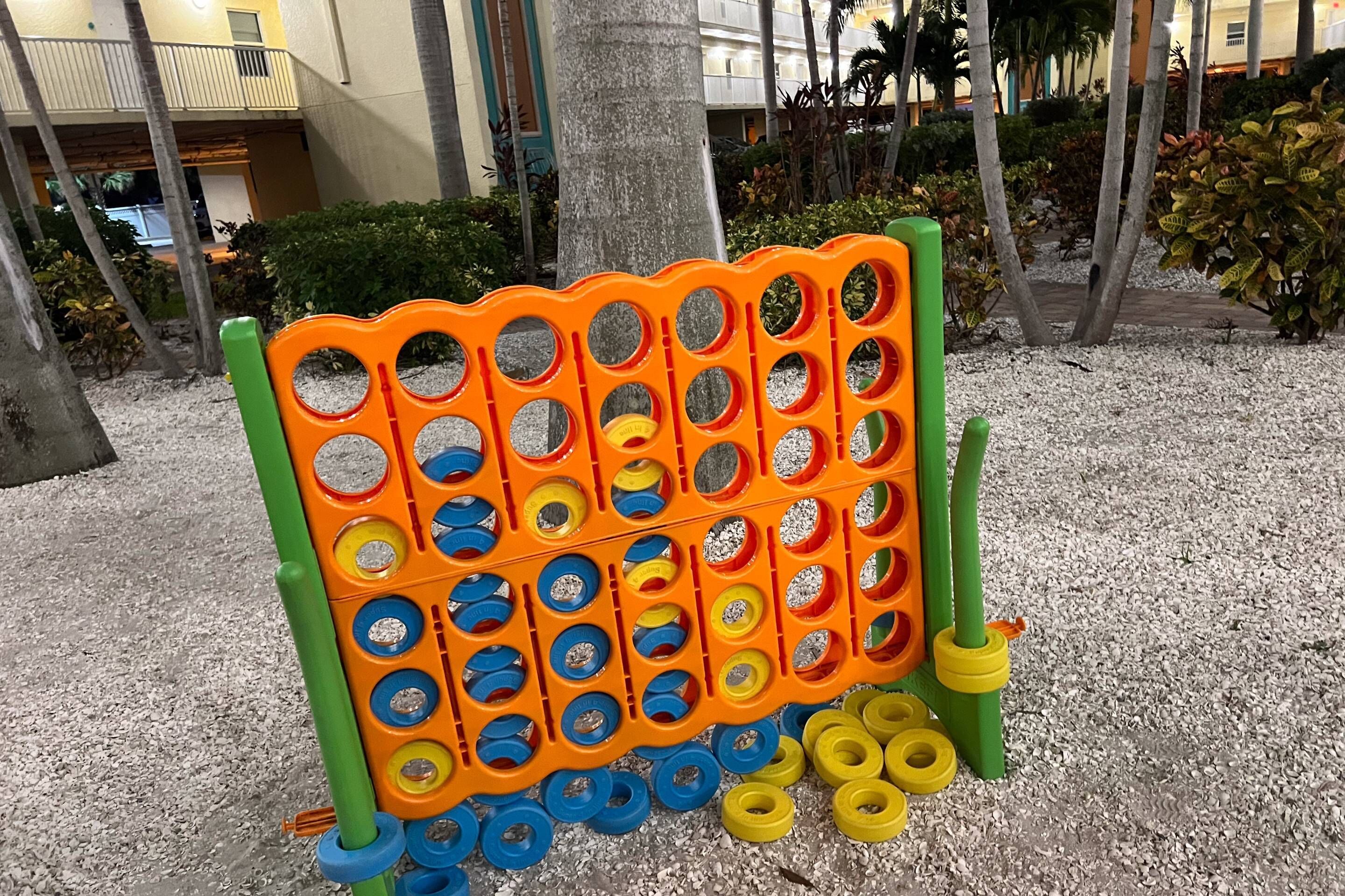 Un panneau perforé avec des chevilles de couleurs vives, installé dans une cour.
