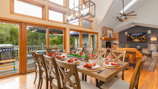 A spacious dining area with a high ceiling, large windows, and a view of the outdoors.