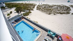 Zona de piscina amb vistes a la platja, cadiretes i ombrelles.