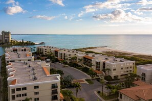 A coastal hotel with multiple buildings, a parking area, and a beach view.