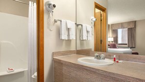 Un baño con lavamanos, espejo, toallero y cabina de ducha.