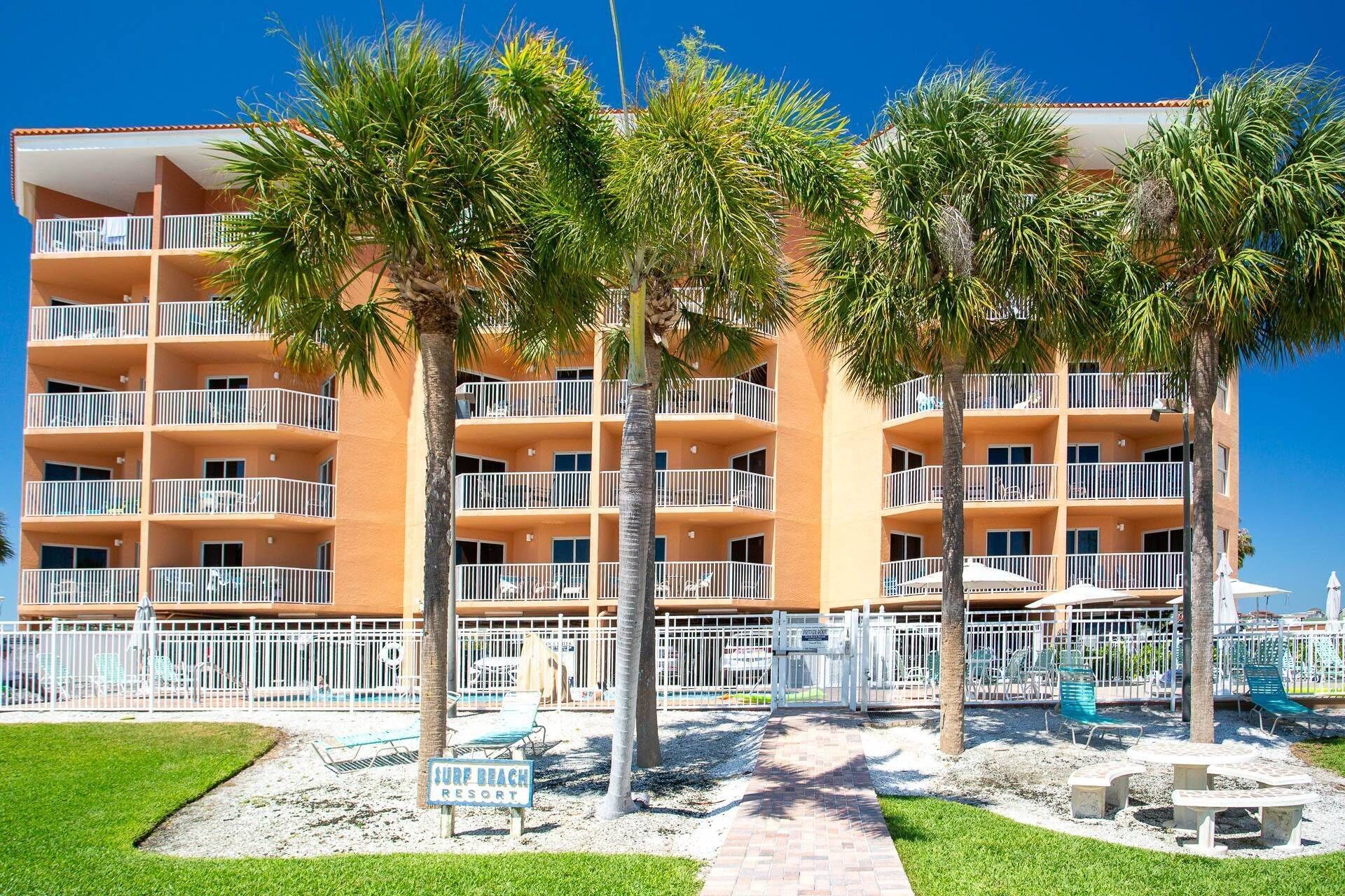A multi-story hotel with balconies, palm trees, and a sign reading 'Surf Beach Resort.'