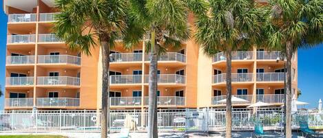 A multi-story hotel with balconies, palm trees, and a sign reading 'Surf Beach Resort.'