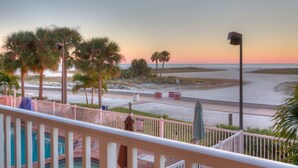 A beach view with palm trees, a pool, and a street in the foreground. - Beachfront Corner Unit ~ Pool ~ Private Balcony ~ Fully Equipped Kitchen ~ Heart of Treasure Island (Treasure Island)