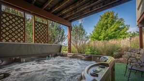 A hot tub with a wooden pergola overhead, surrounded by greenery and trees. - Outdoor Hot Tub, Pool Table, Huge Fire Pit - Close 2 Pools! (Galena)