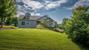 A two-story house with a front porch, a small attached garage, and a well-maintained lawn.
