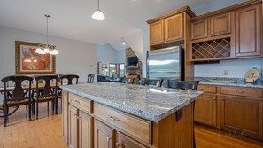 A spacious kitchen with granite countertops, wooden cabinets, and a built-in refrigerator.