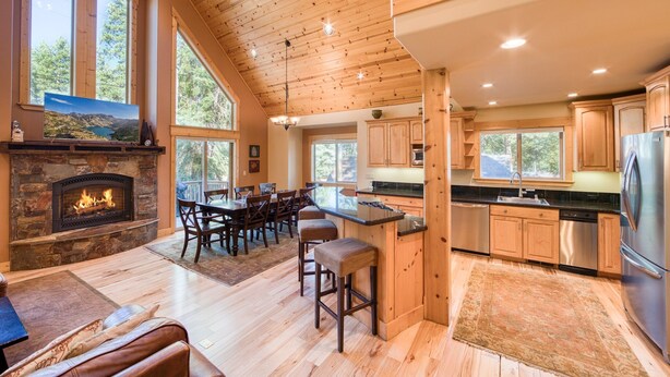 Una cocina amplia con armarios de madera, una chimenea de piedra y ventanas grandes.