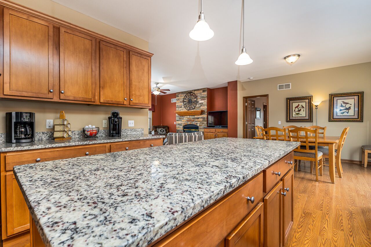 A kitchen with granite countertops, wooden cabinets, and a dining area with a table and chairs.
