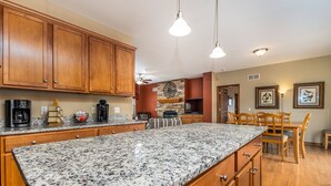 A kitchen with granite countertops, wooden cabinets, and a dining area with a table and chairs.