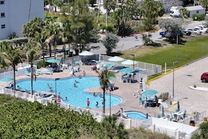 A swimming pool area with multiple pools, sun loungers, and umbrellas.