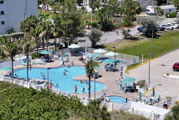 A swimming pool area with multiple pools, sun loungers, and umbrellas.