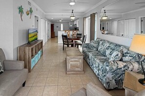 Un vaste espace de vie comprenant un canapé, une table basse et un téléviseur posé sur un meuble en bois.