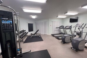 A gym with treadmills, elliptical machines, dumbbells, and a squat rack.