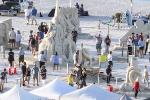 A sandy area with large white sculptures and tents.