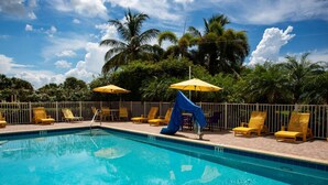 A swimming pool with lounge chairs and umbrellas, surrounded by palm trees. - Modern 2Br/2Ba Beachfront Condo with an Incredible View. Amenities, Pool, Beautiful Beach (Treasure Island)