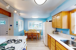 Enjoy meals at the dining table in this cozy kitchen area with a gas stove and stainless steel sink.