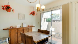 A dining area with a wooden table and chairs, a hanging flower basket, and a ceiling light fixture.