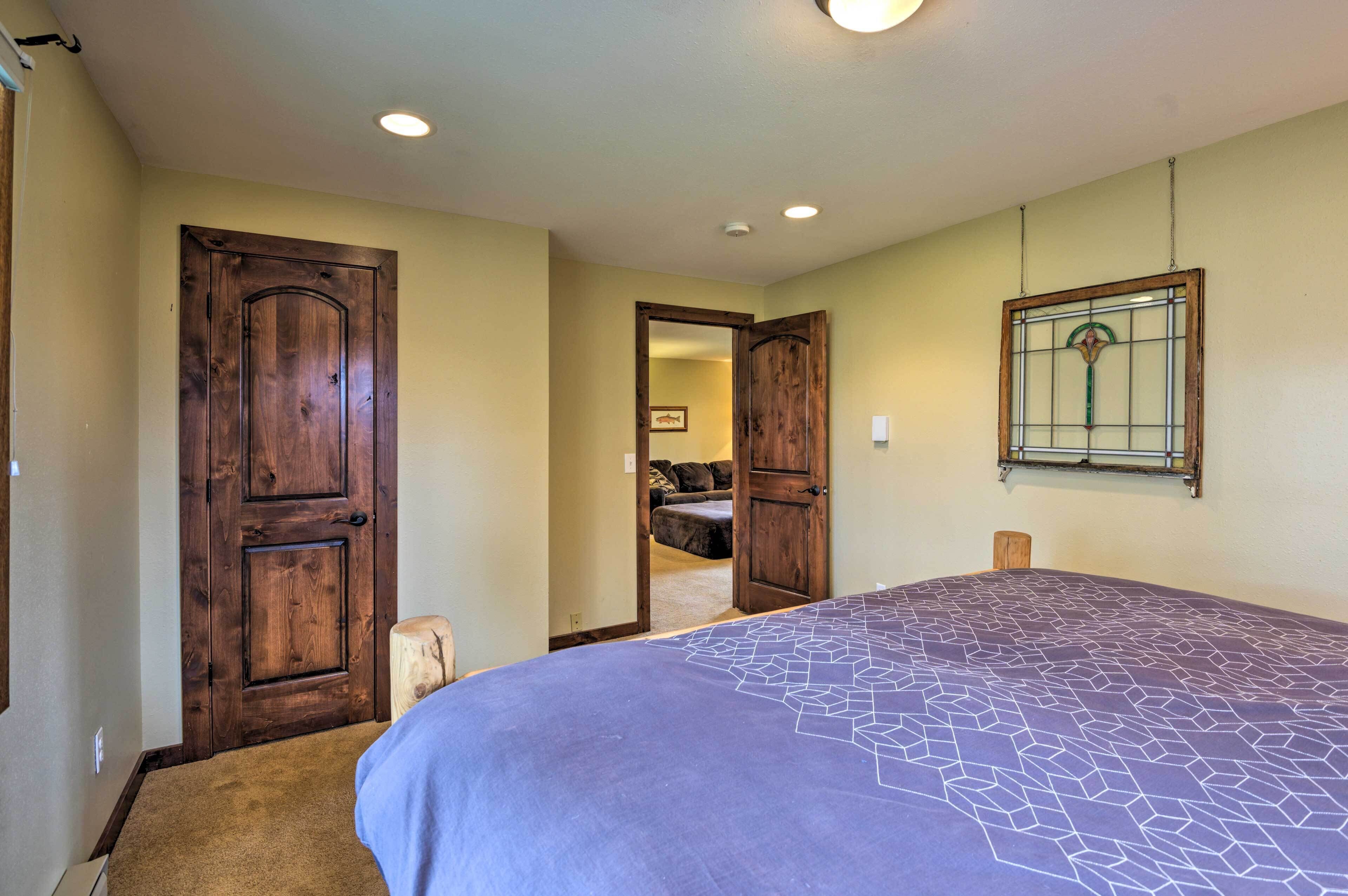 Un dormitorio con una cama grande, puertas de madera y un taburete pequeño.