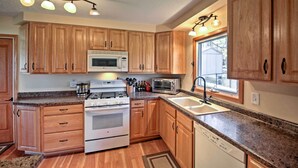 Eine Küche mit Holzausstattung, einem Herd, einer Mikrowelle, einem Toaster und einem Fenster, das für natürliches Licht sorgt.