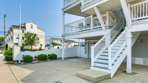 A multi-story building with a white exterior, a central staircase, and a small front porch area. - Condo w/ Deck: Walk to Beach & Convention Center! (Wildwood)