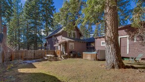 Une maison à deux étages avec un jardin clôturé, un jacuzzi et un grand arbre.