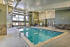 An indoor swimming pool with clear glass walls, a tiled floor, and a ceiling with visible ductwork and lighting fixtures. - Riverside Condo in Downtown Winter Park! (Winter Park)