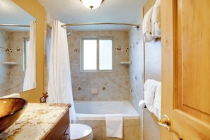 A bathroom with a bathtub, toilet, and a large mirror. - Riverside Condo in Downtown Winter Park! (Winter Park)