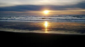Une plage où le soleil se couche sur l’océan, créant une surface d’eau calme et propice à la contemplation.
