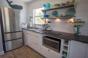 A modern kitchen with stainless steel appliances, a granite countertop, and a window with a view.
