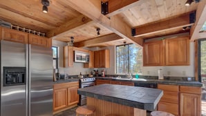 A modern kitchen with wooden cabinets, stainless steel appliances, and a large island with stools.